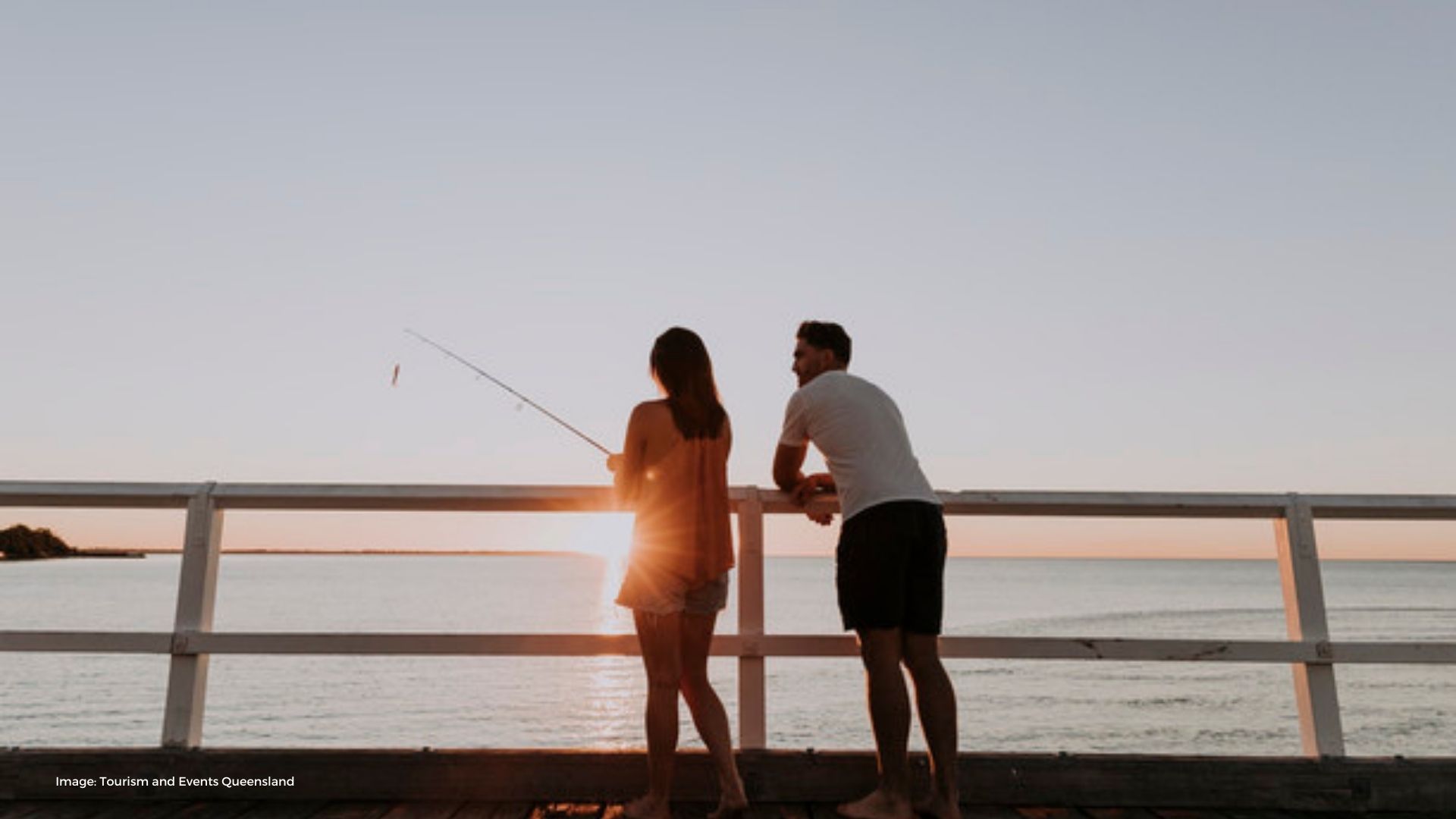 Couple standing on Hervey Bay pier at sunset | Tourism & Events Queensland