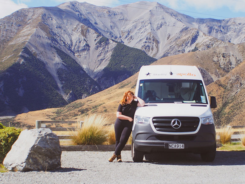 Woman standing next to rental campervan in New Zealand
