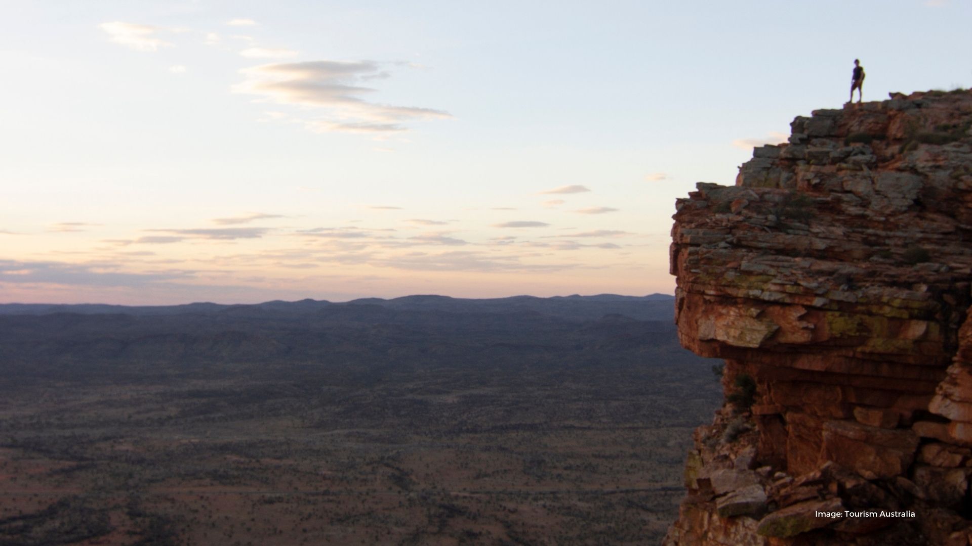 Person looking out over outback landscape from rocky cliff | Tourism Australia