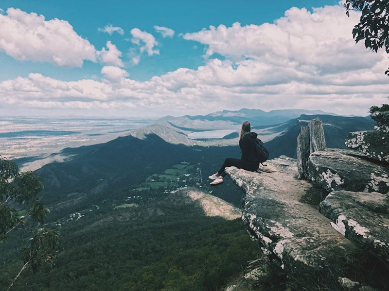 Girl sitting on edge of Boroka Lookout with scenic background 