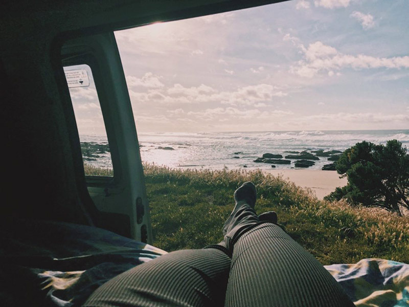 Girls legs hanging out the side of a campervan looking out at the view