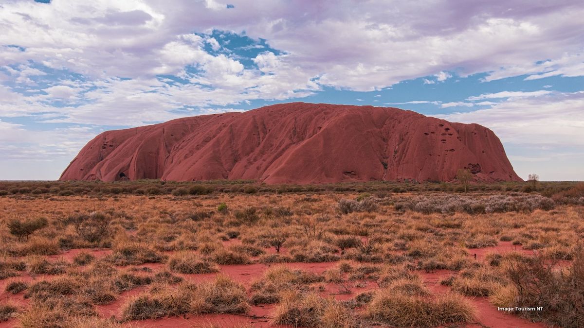 Gigantic red rock surrounded by dry outback landscape