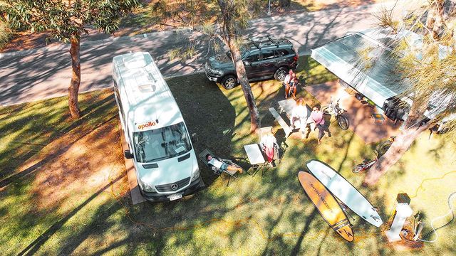 Shot from above of Apollo campervan and people sitting around at campsite