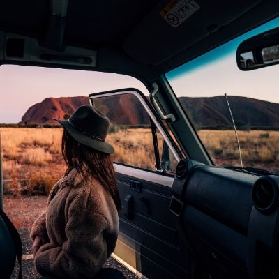 Women in Apollo Campervan in front of Uluru