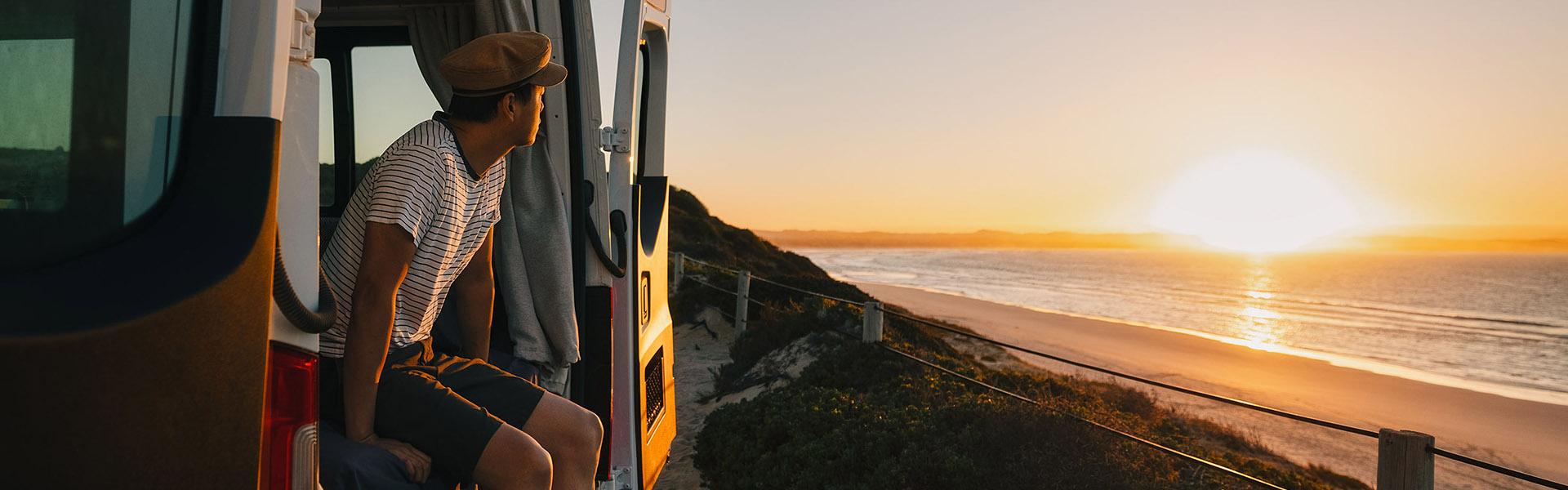Young man sitting in Apollo camper enjoying sunset at Almonta Beach, South Australia